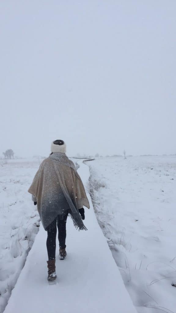 Girl with a hair band walking on a long snowy path