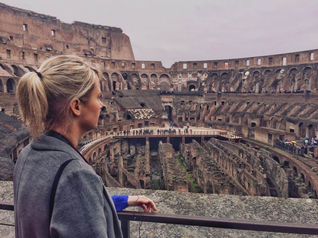 Blonde girl standing in the Colosseum looking at the stage in front of her