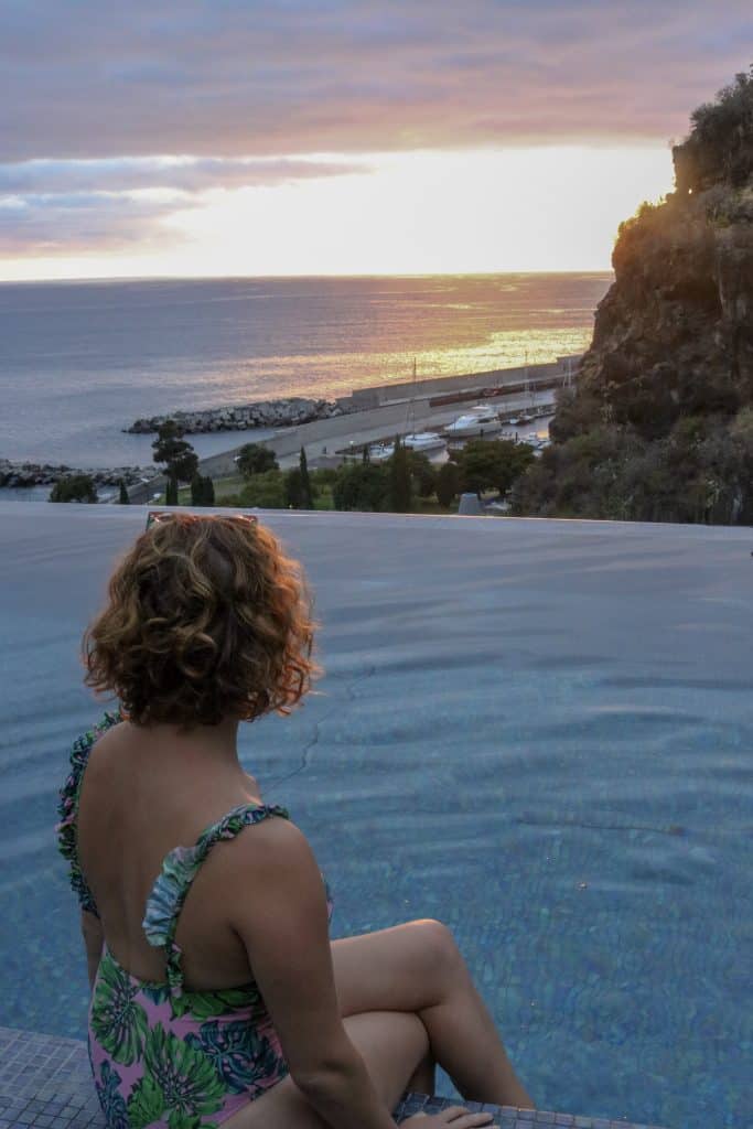 Girl sitting on the edge of an infinity pool looking at the ocean