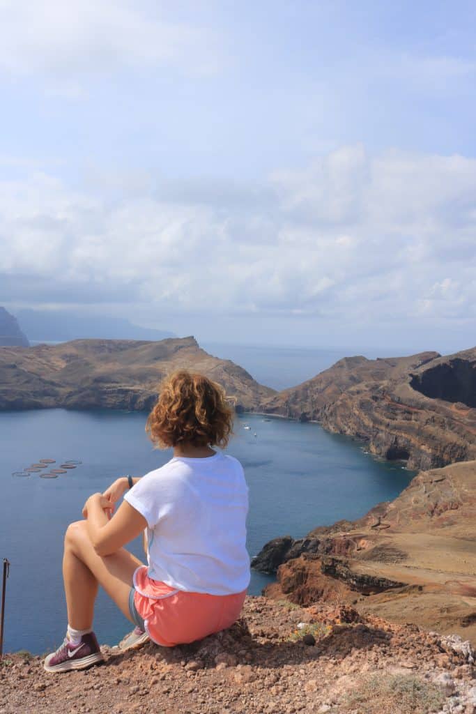 Girl sitting down on the top spot of the hike Ponte De Sao Laurenco overlooking the ocean