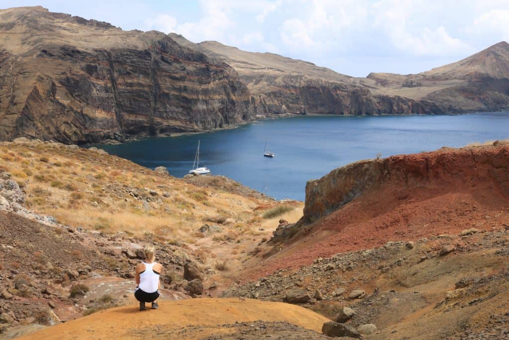 Girl kneeling in front of a lake and vulcanic orange soil