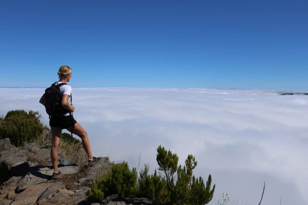 Girl with a backpack on looking over the clouds