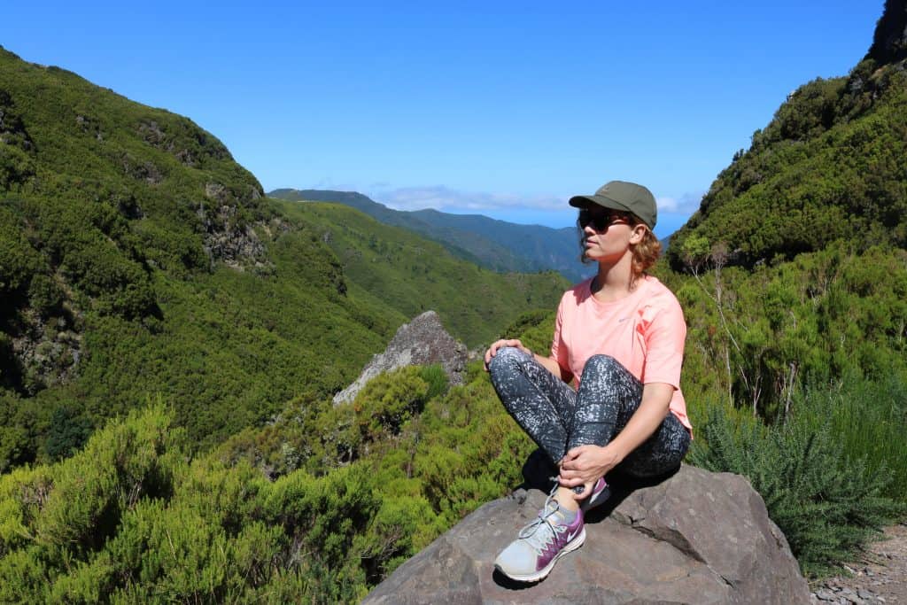 Girl with cap on a rock in between mountains in Madeira