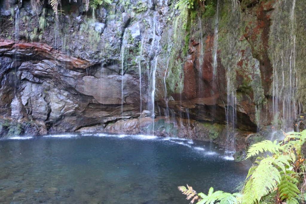 Clear blue water and 25 tiny waterfalls flowing into the lagoon with rocks behind it