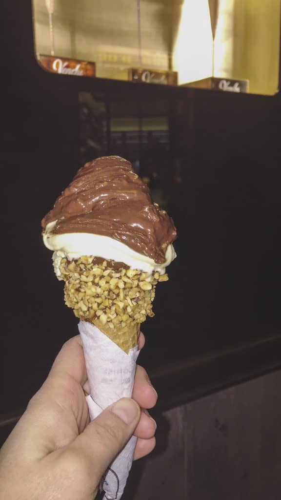 Hand tot holds an icecream with chocolate and nuts