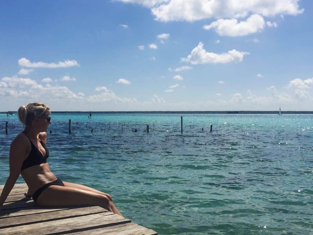 Girl sitting on a dock with a view over a blue lagoon