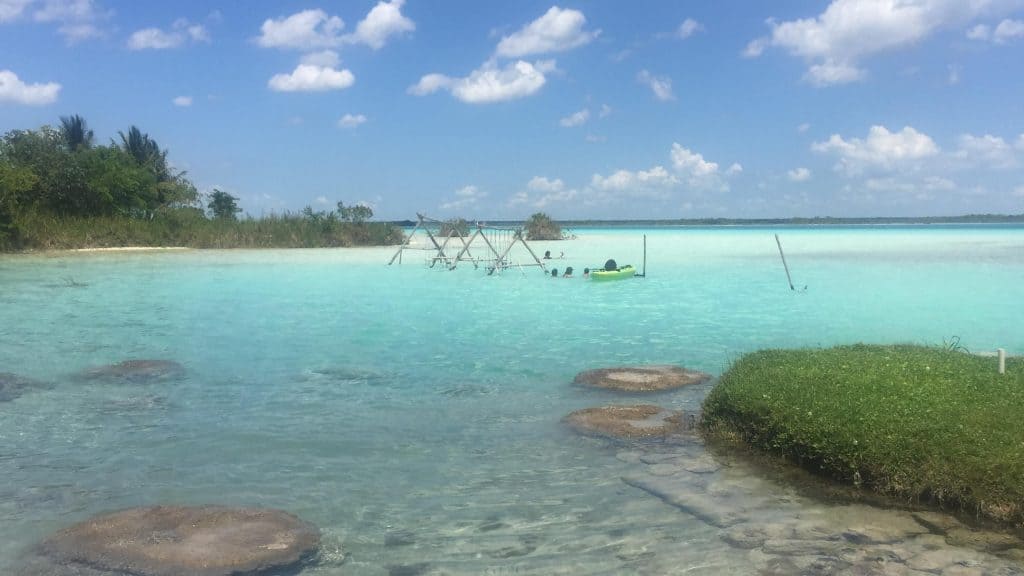 Clear blue water with two swings in it and a clear blue sky with a few white clouds