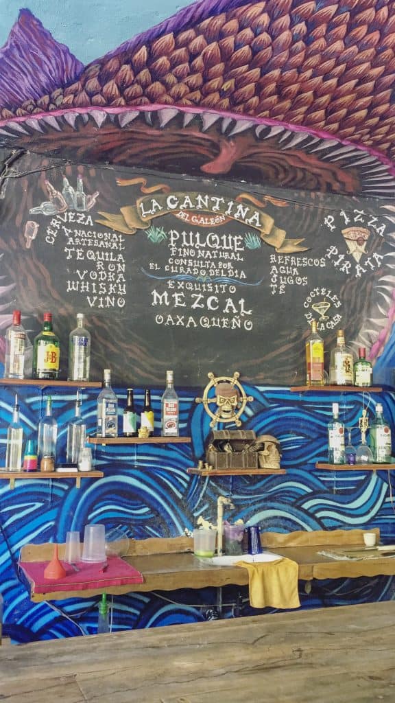 Mexican bar with a painted wall and lot's of bottles of booze