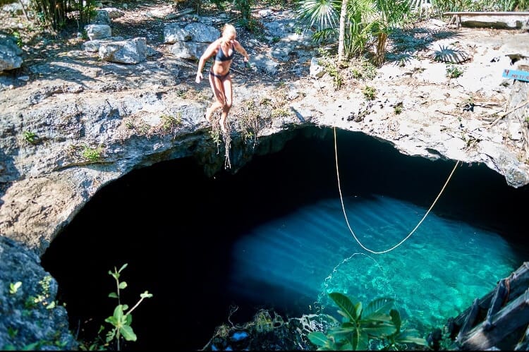 Girl jumping in cenote calavera in Tulum 
