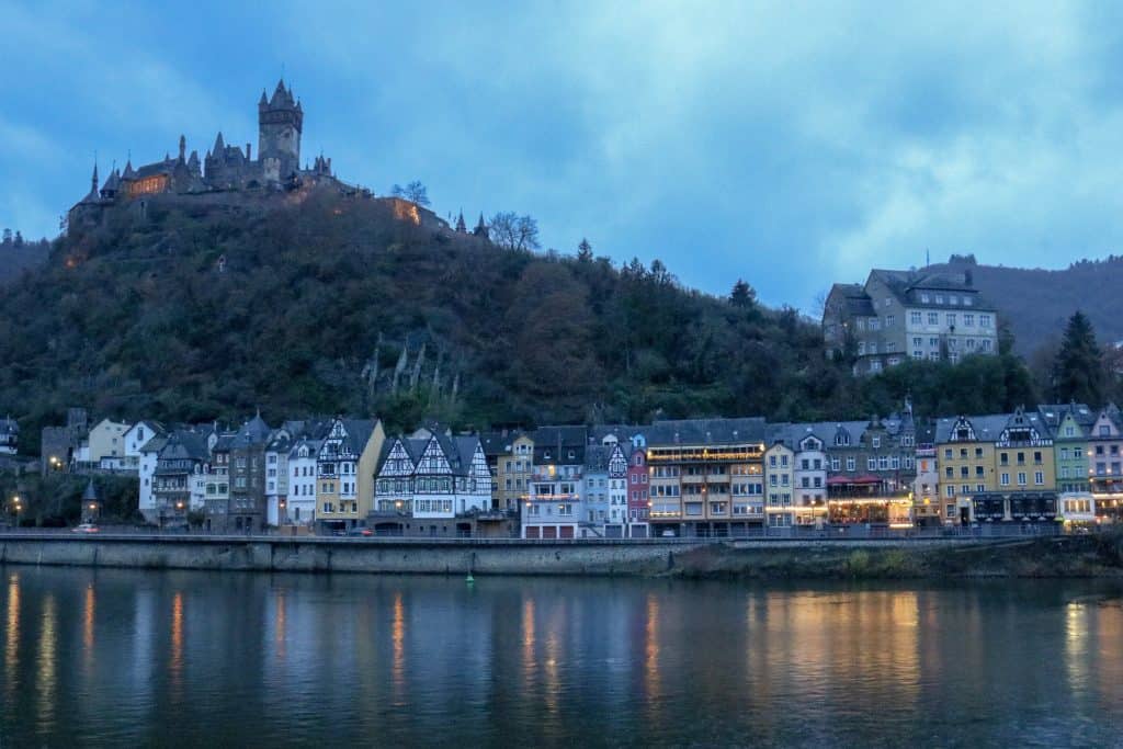 Castle on a hill with houses and a river at the bottom in the early evening light