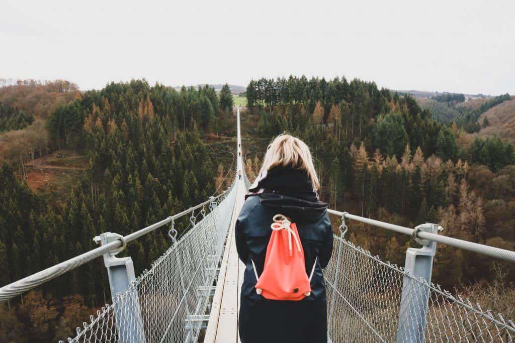 Girl with pink backpack standing at the beginning of a bridge