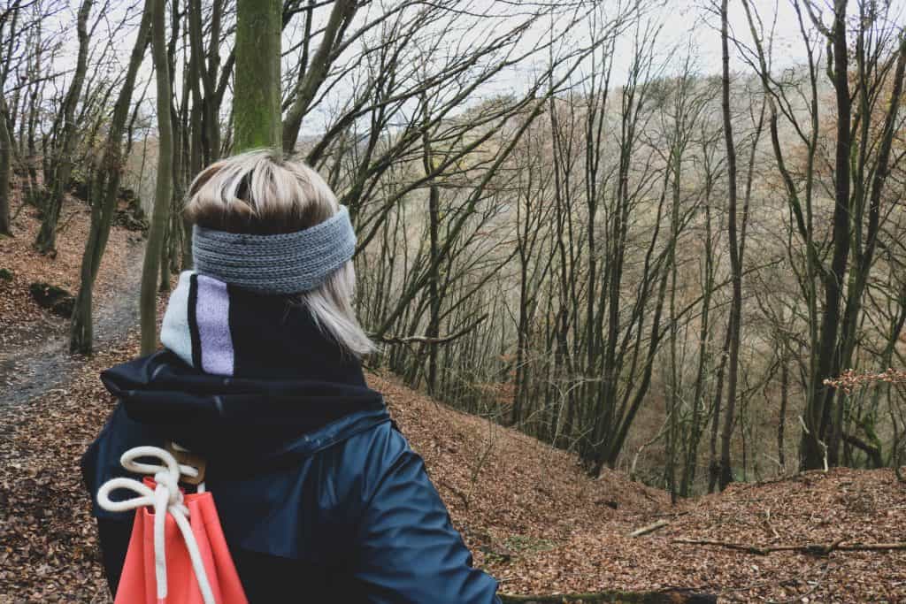 Girl with a headband on looking at the trees in a forest