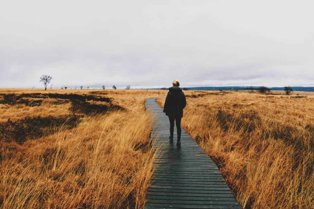 Girl walking on a path surrounded by dry yellow grass