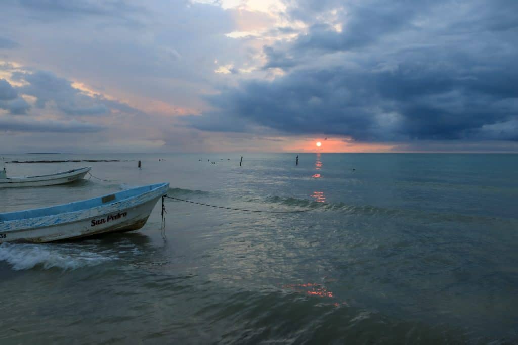 Sunset with dark blue clouds over the ocean and a few boats in the ocean