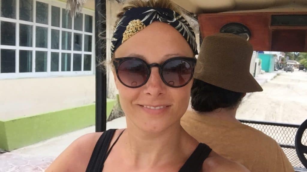 Girl with sunglasses and headband on sitting in the back of a golf cart