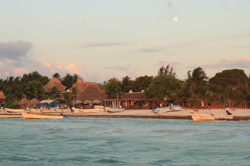 Sunset over the ocean and a beach village with palmtrees