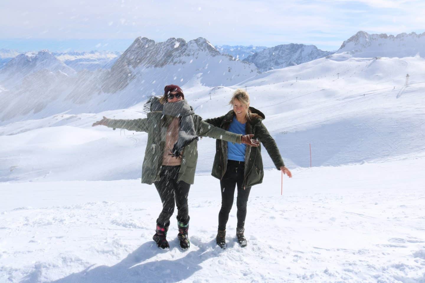 Two girls playin in the snow and throwing it in the air