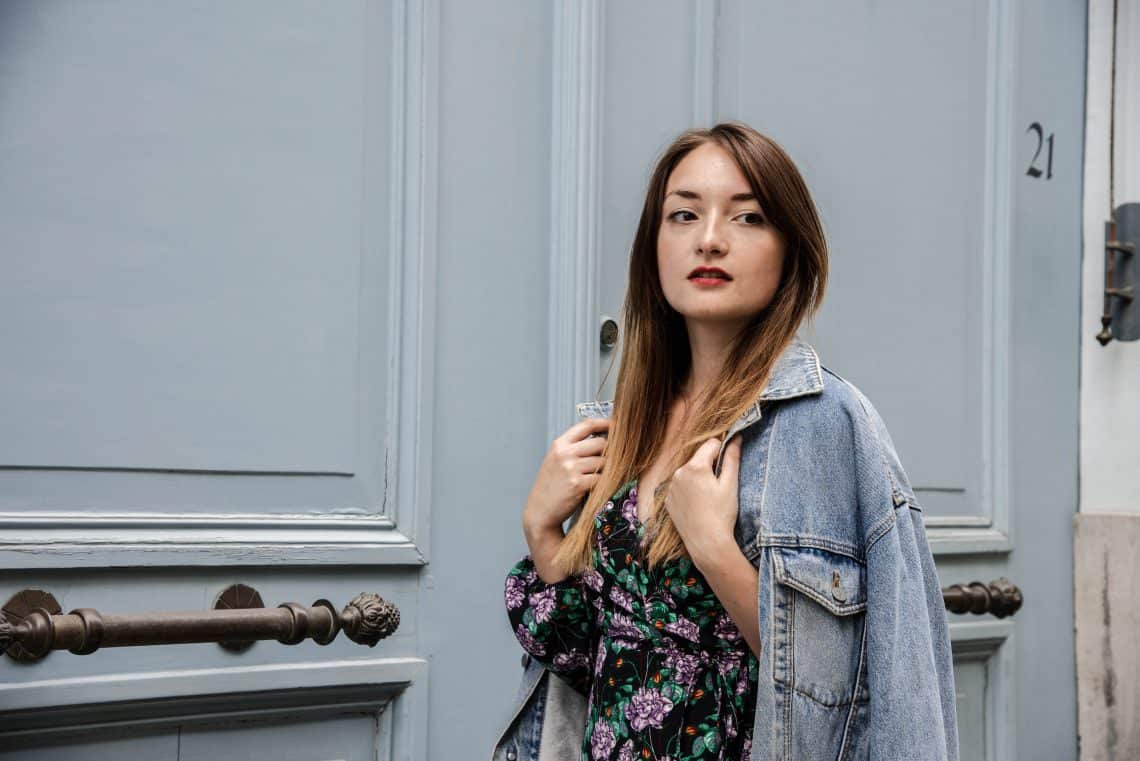 Girl with jeans jacket standing in front of a blue door