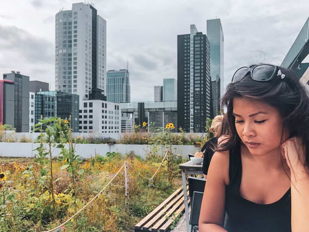 Skyscrapers behind a girl having lunch at ophetdak rotterdam