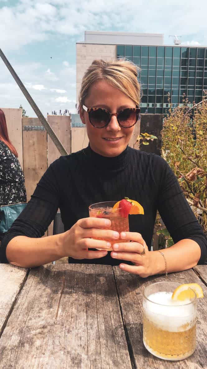 Girl holding a cocktail at ophetdak rooftop rotterdam